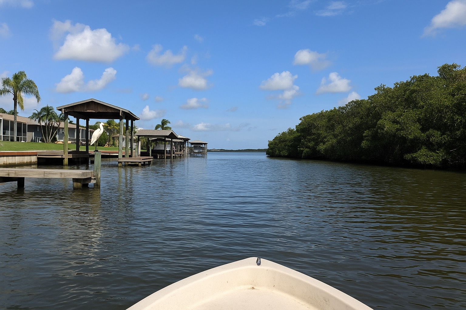 Daylight aerial of a Merritt Island residential canal, seawalled back yards with private docks and covered boat lifts.